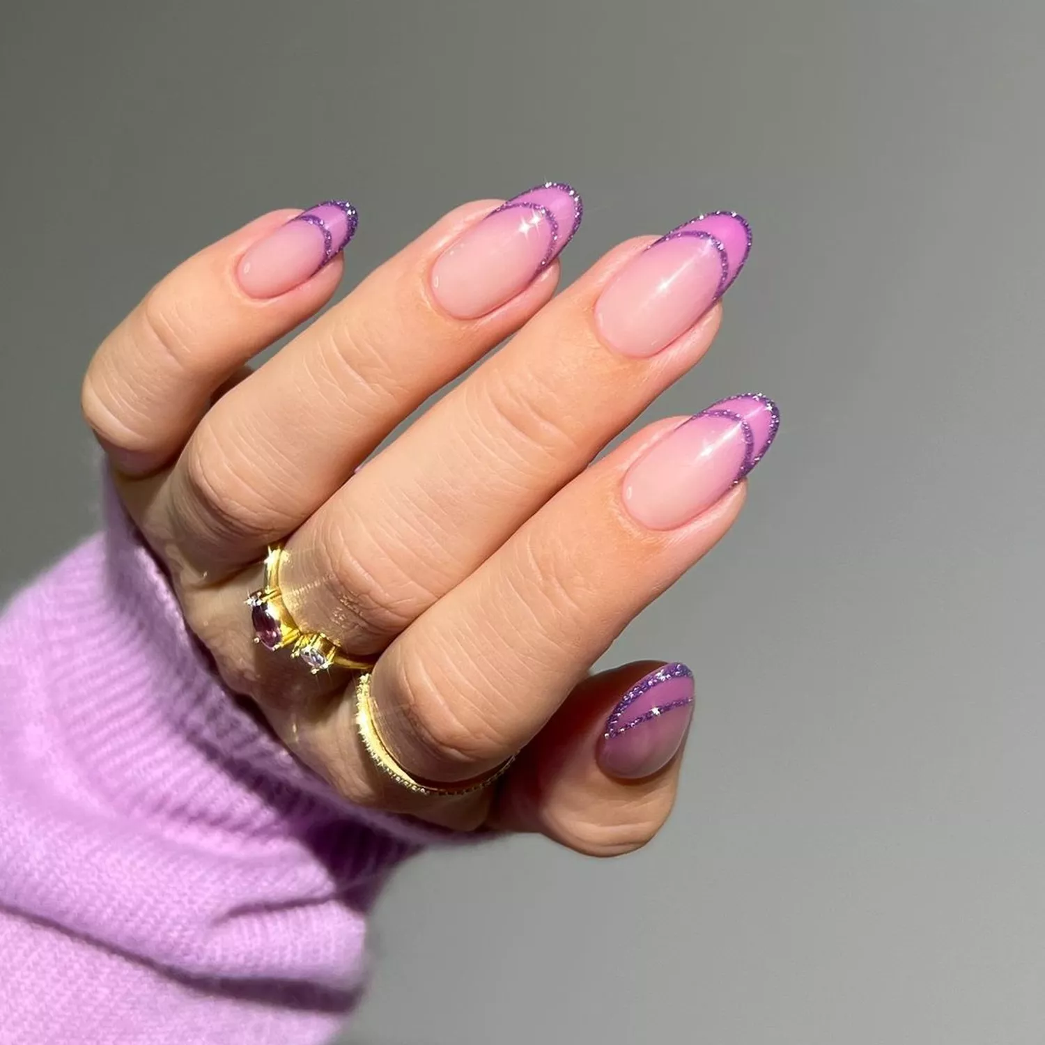 a pink base manicure with purple tips outlined in glitter