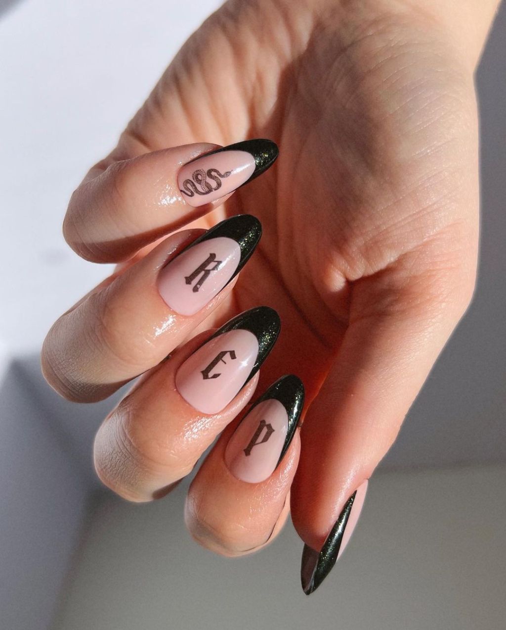 glittery black French tip Taylor Swift nails with snake and gothic lettering designs inspired by the Reputation album on the Eras Tour