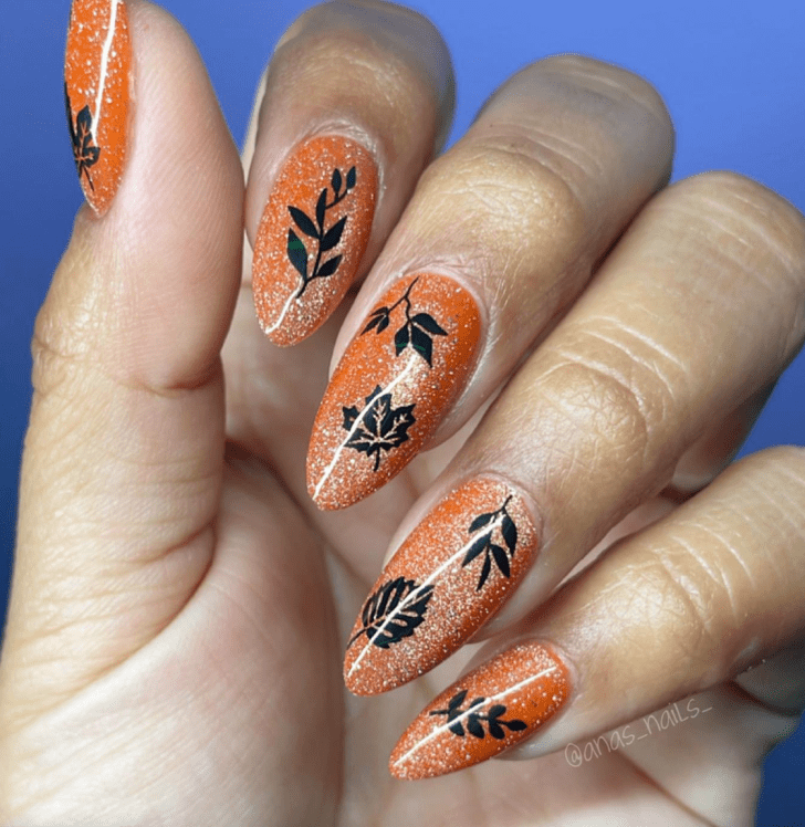 glittery orange manicure with a black falling leaf design inspired by the Evermore Era