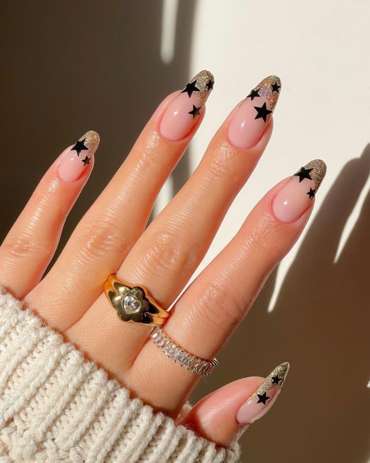 gold glitter french tip new years nails with black star designs