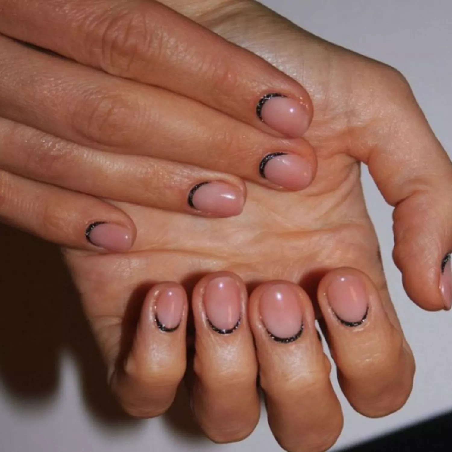 Nude nails with sparkly black halos around the cuticles.