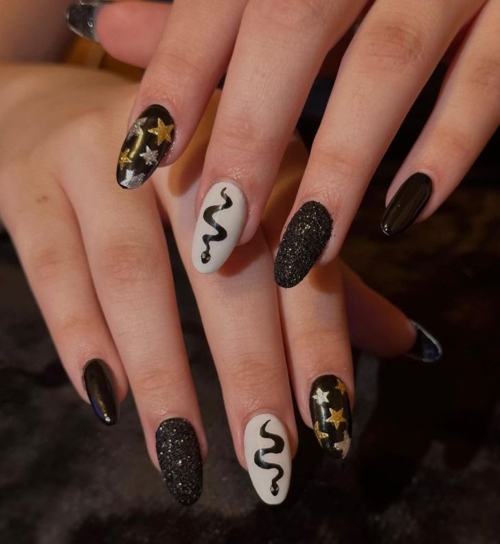 mismatched glittery black Taylor Swift nails with snake and star designs inspired by the Reputation album on the Eras Tour