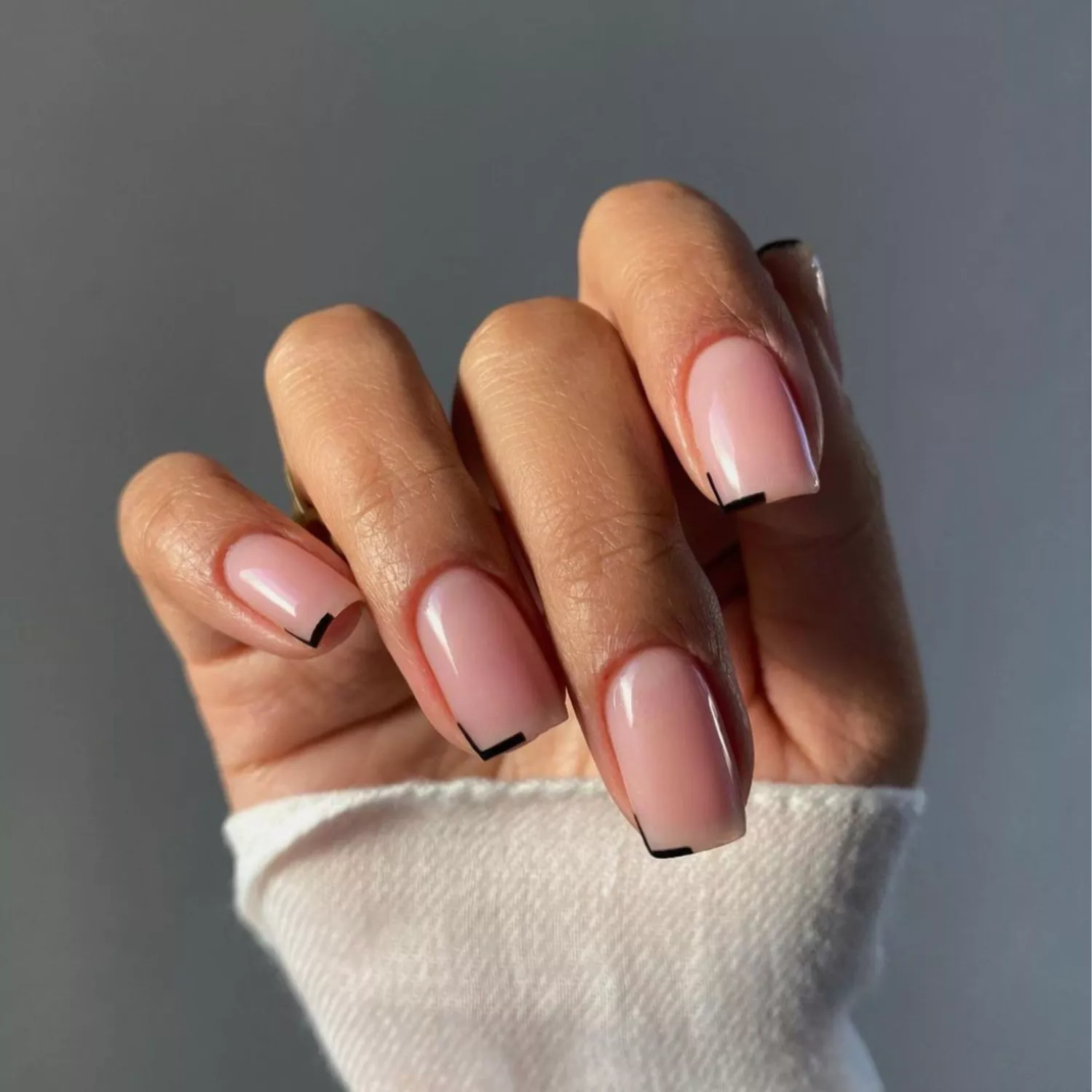 Nude manicure with tiny black corner details.