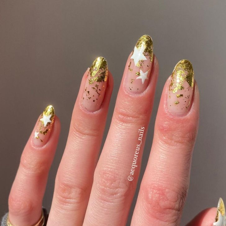 ombre gold foil Taylor Swift nails with a white star design inspired by the Fearless album on the Eras Tour