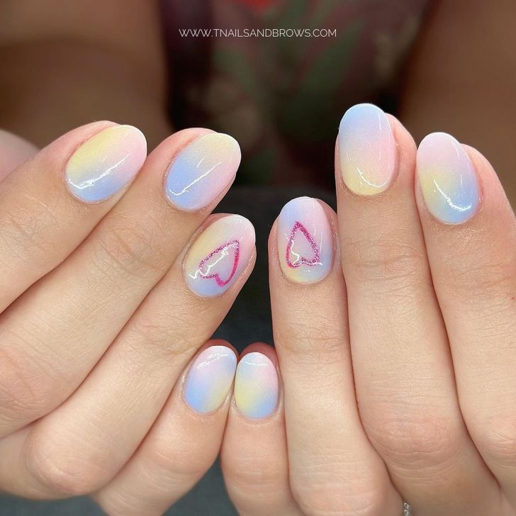 pastel rainbow ombre Taylor Swift Eras tour nails with a glittery pink heart design on one finger inspired by the Lover album