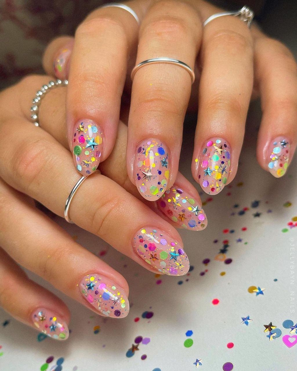 rainbow confetti themed new years nails with metallic star designs