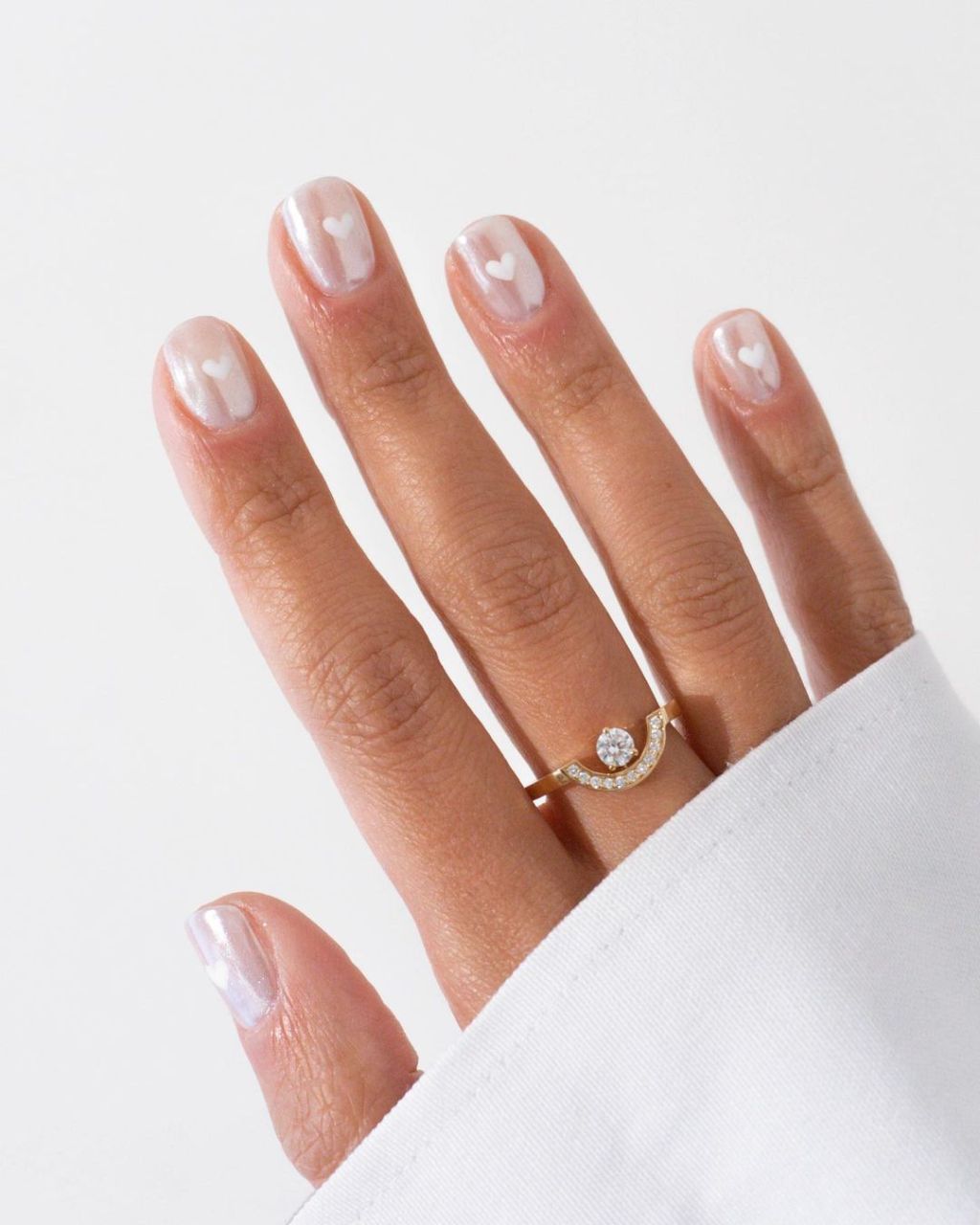 bride showing off her shimmery chrome short wedding nails with a small white heart design