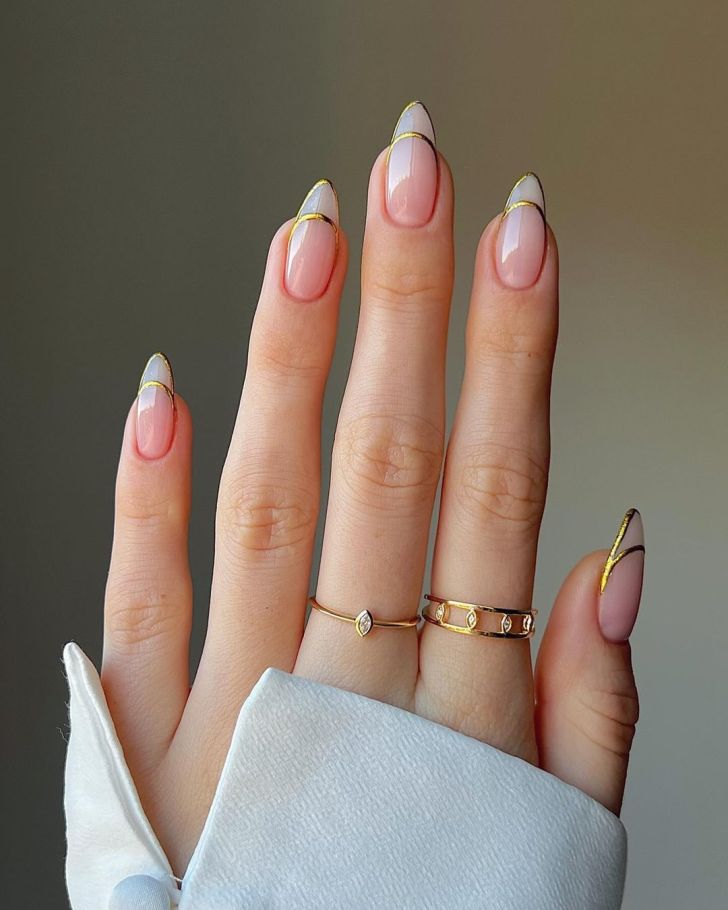 simple nude new years nails with metallic gold french tip outlines and an almond shaped design