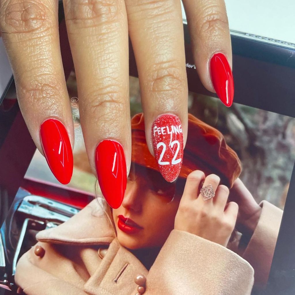 simple Taylor Swift nails with a sparkly "Feelin' 22" design on one finger inspired by the Red album on the Eras Tour