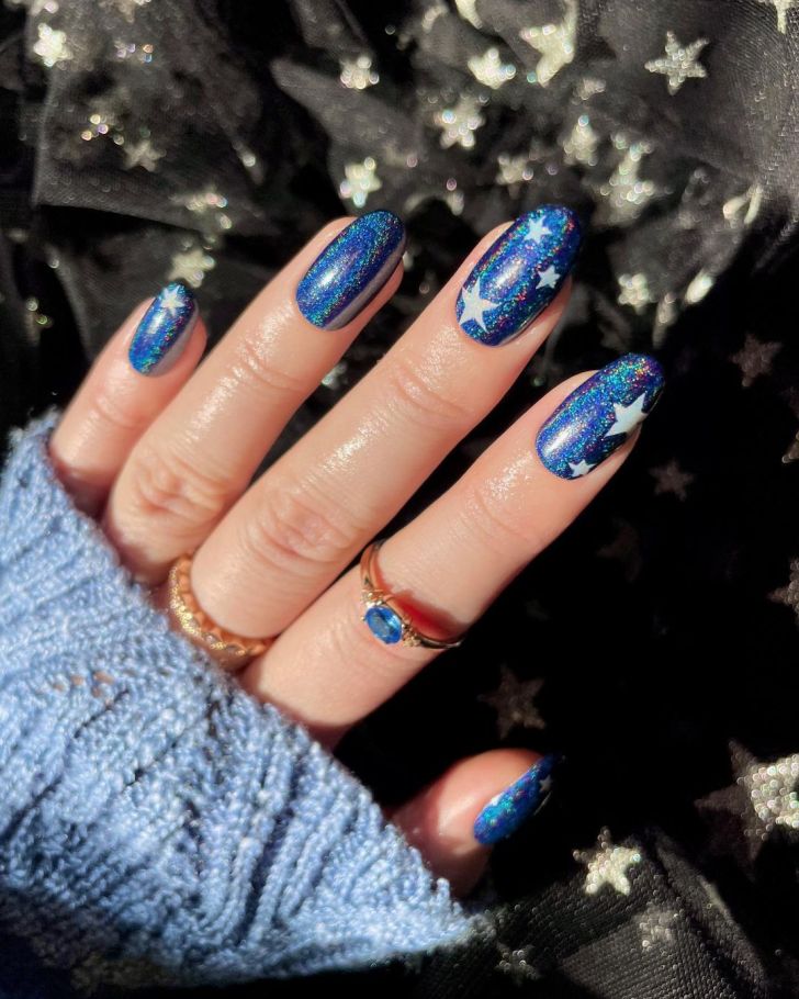 glittery blue Taylor Swift nails with white star design inspired by the Midnights album on the Eras tour