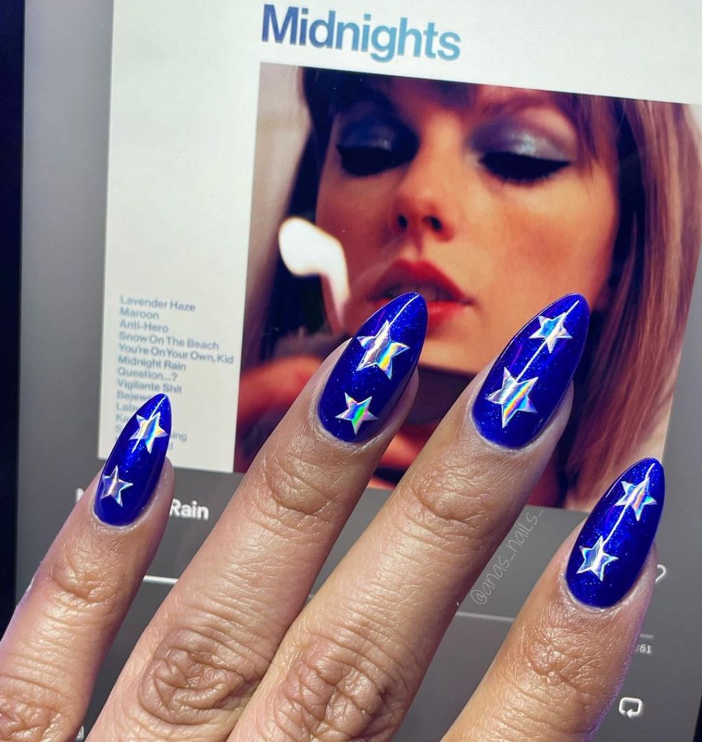 sparkly royal blue Taylor Swift nails with a metallic silver star design inspired by the Midnights album on the Eras tour