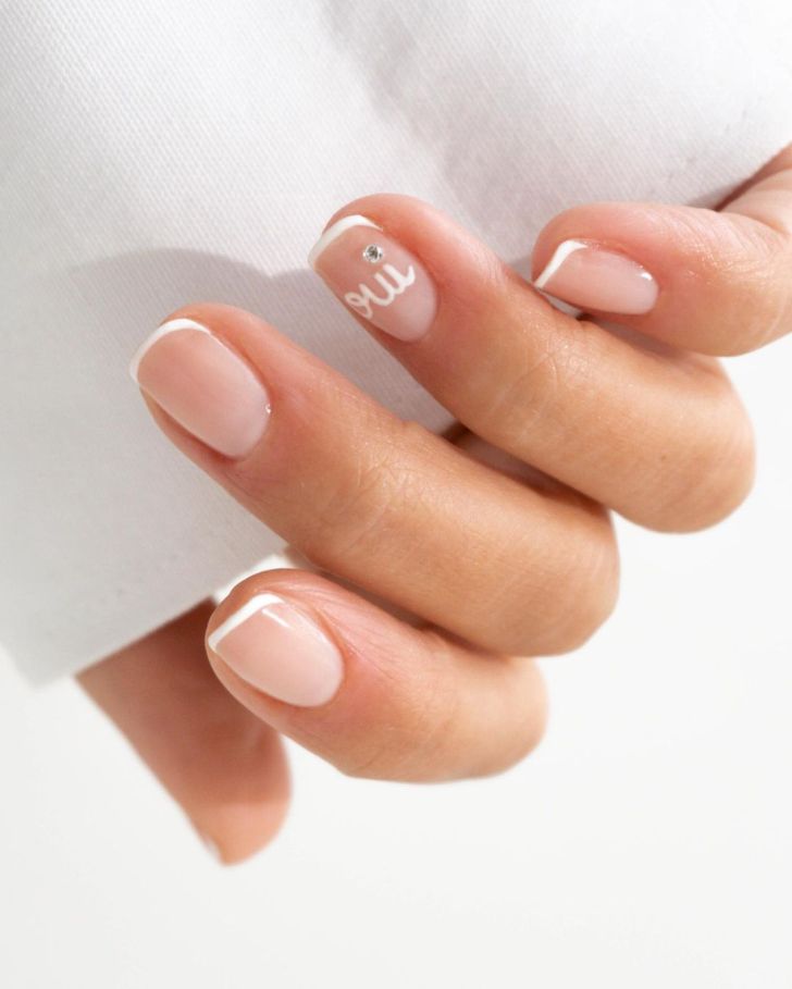 unique short french tip white wedding nails for the bride with rhinestone detail and oui written on the ring finger