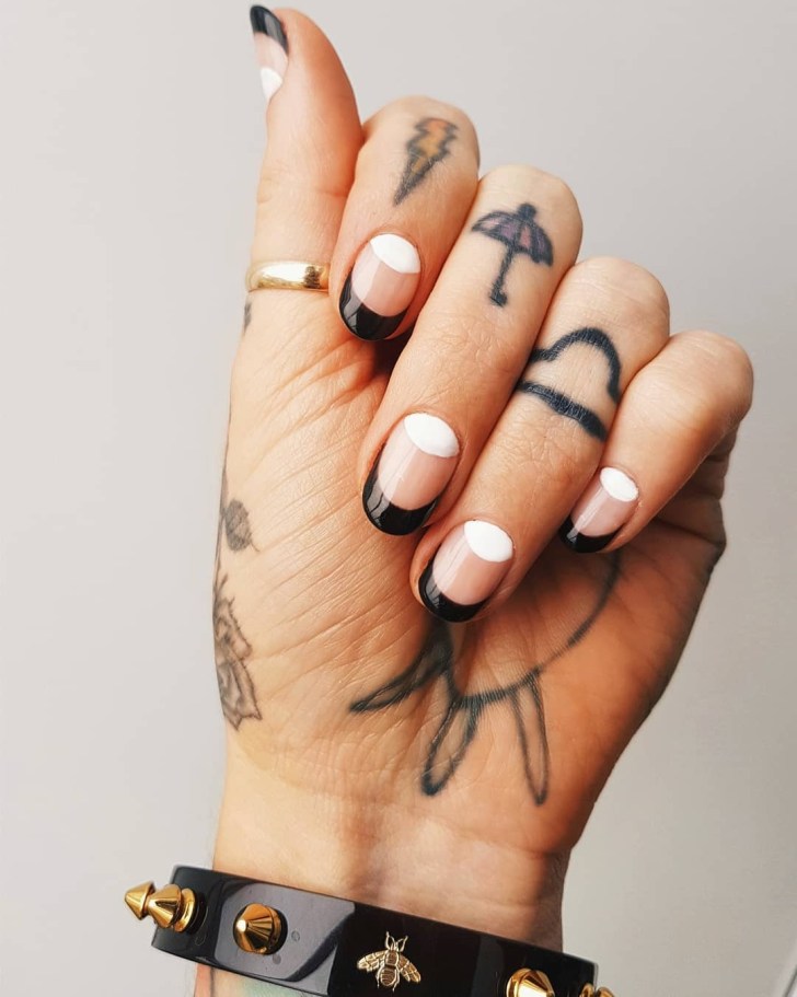 simple white and black wedding nails on a tattooed hand