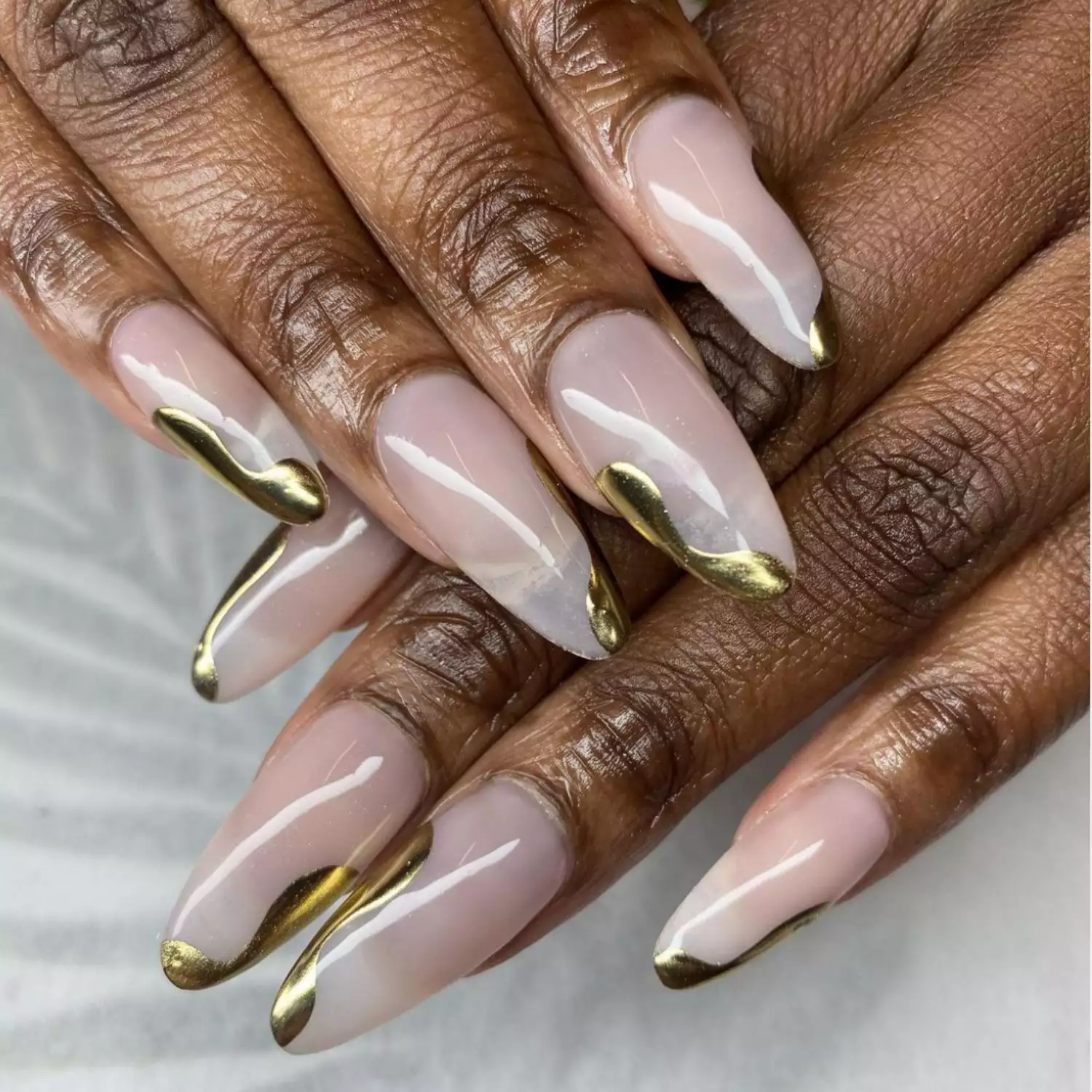 White, milky nails with dripping gold, swirling tips.