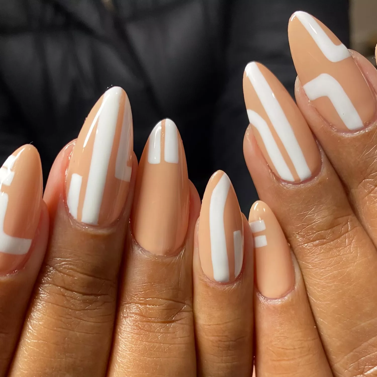 Neutral almond-shaped manicure with white art deco line designs