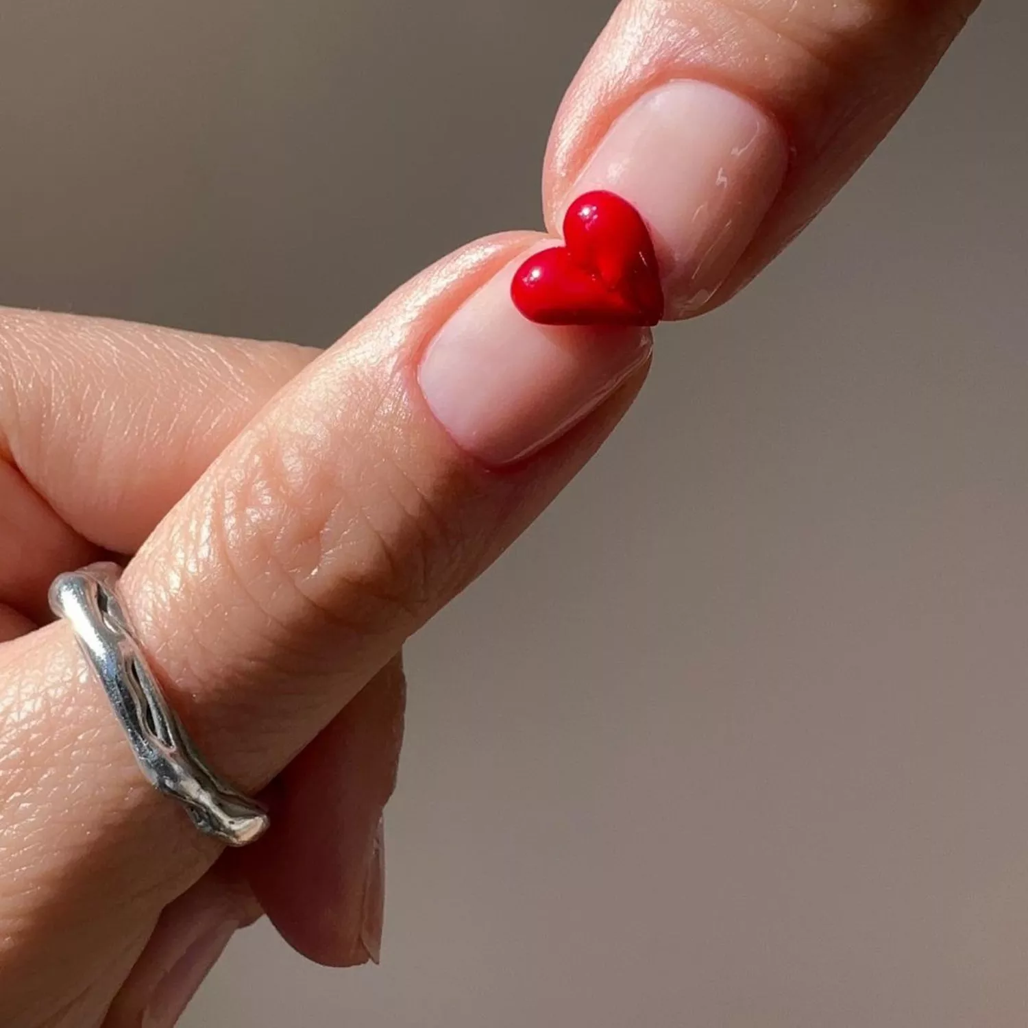 Manicure with minimalist clear base and half-heart 3D design on each nail