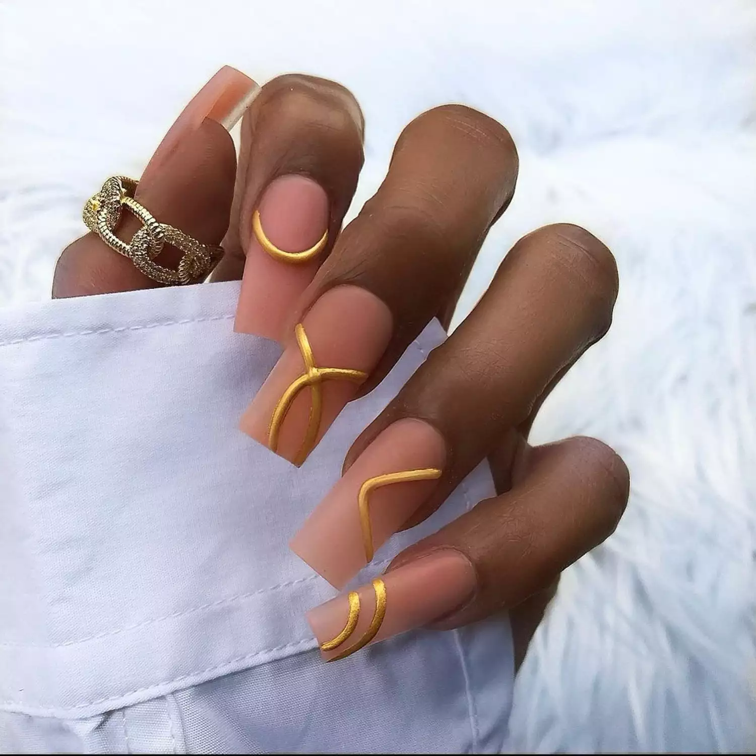 Close-up of neutral matte square-tip nails with 3D gold accents