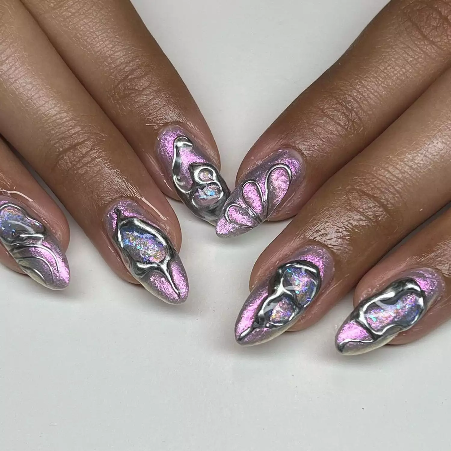 Close-up of manicure with purple iridescent base and opalescent 3D swirl designs