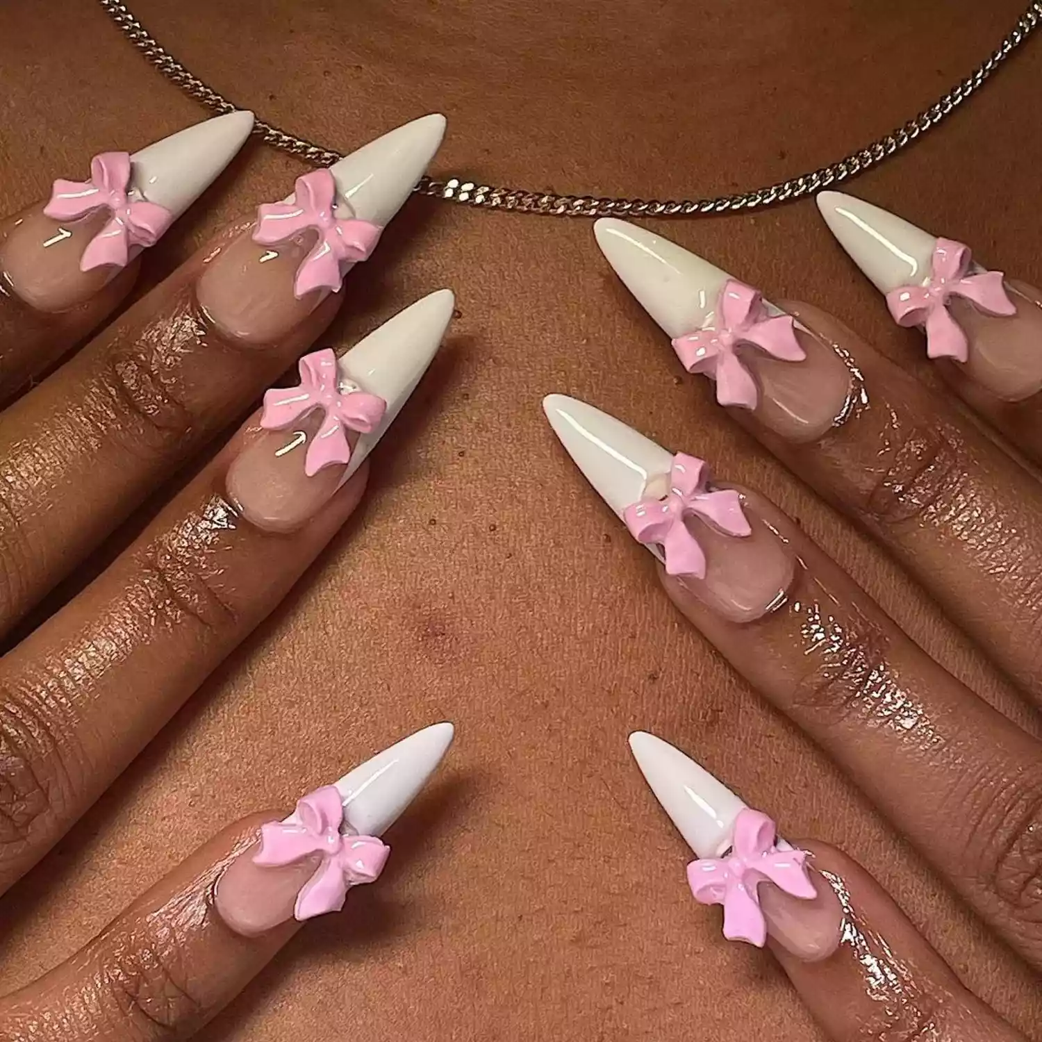 Close-up of long manicure with white French tip and 3D pink bow designs