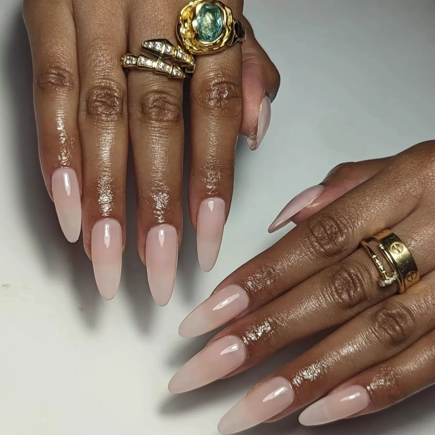 Sheer pink long almond-shaped nails with gold rings