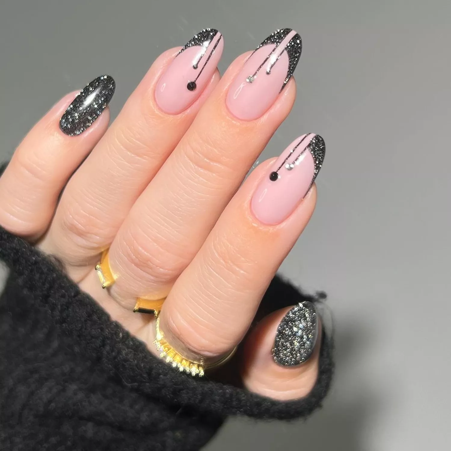 Manicure with neutral base, some solid black glitter nails, and some art deco black glitter drip French tips