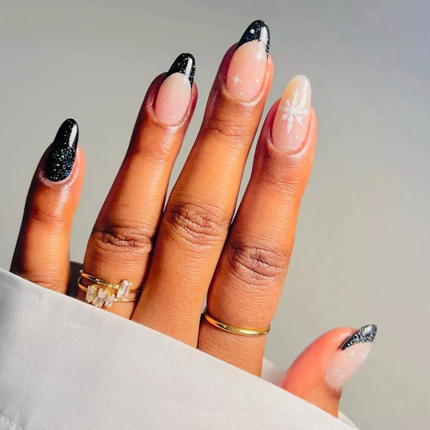 Manicure with black glitter nails and French tips and white snowflake designs