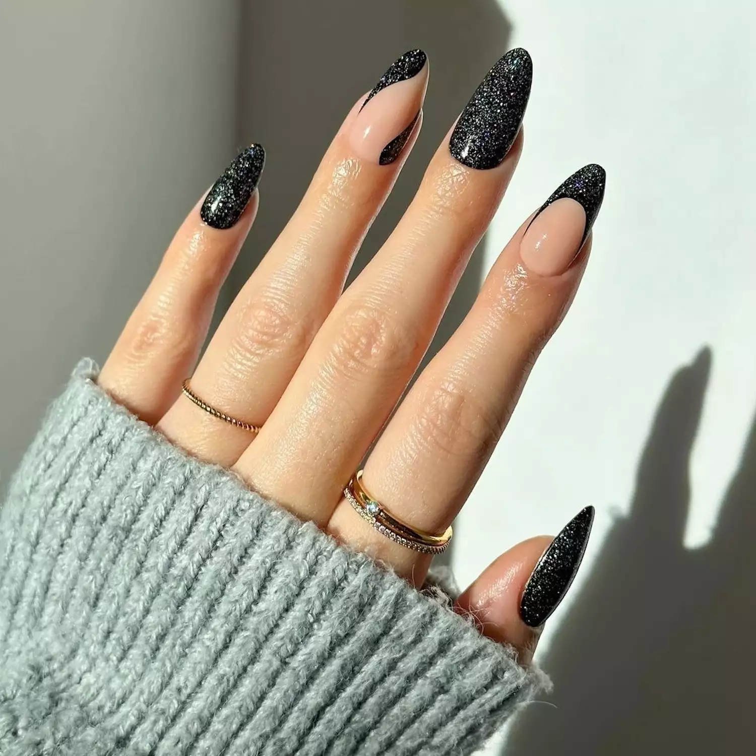 Manicure with black glitter full nails, French tips, and abstract wave designs