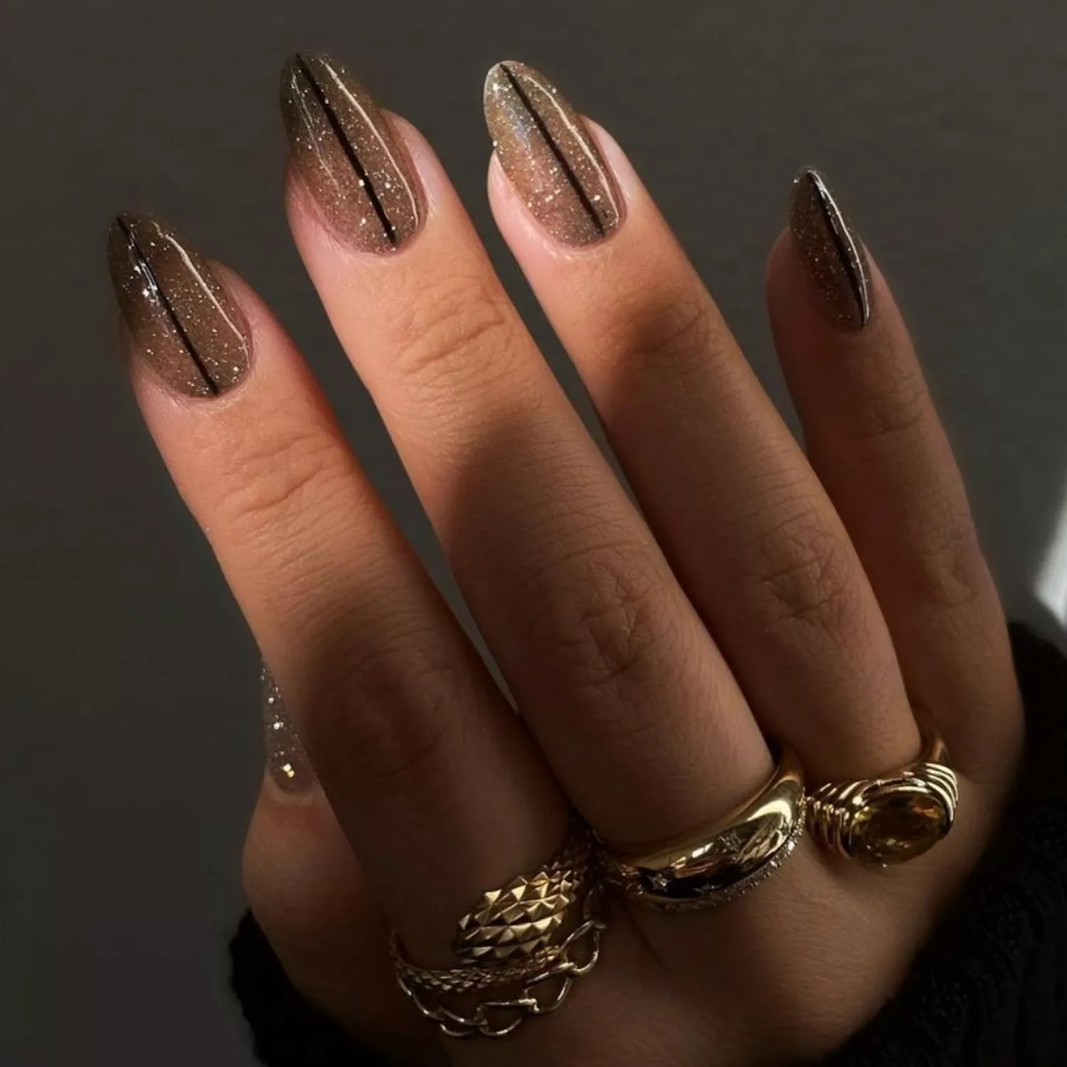 Dark champagne glitter manicure with black stripe detail