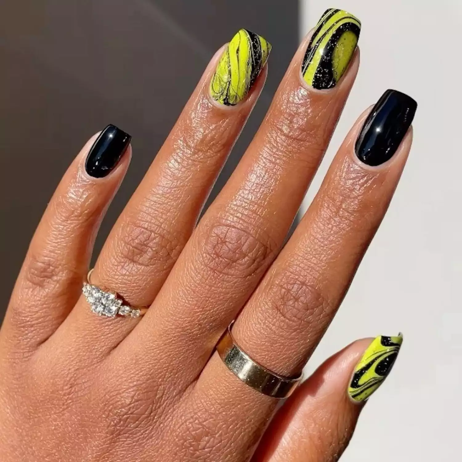 Manicure with glossy black nails and black and yellow glitter marble accent nails