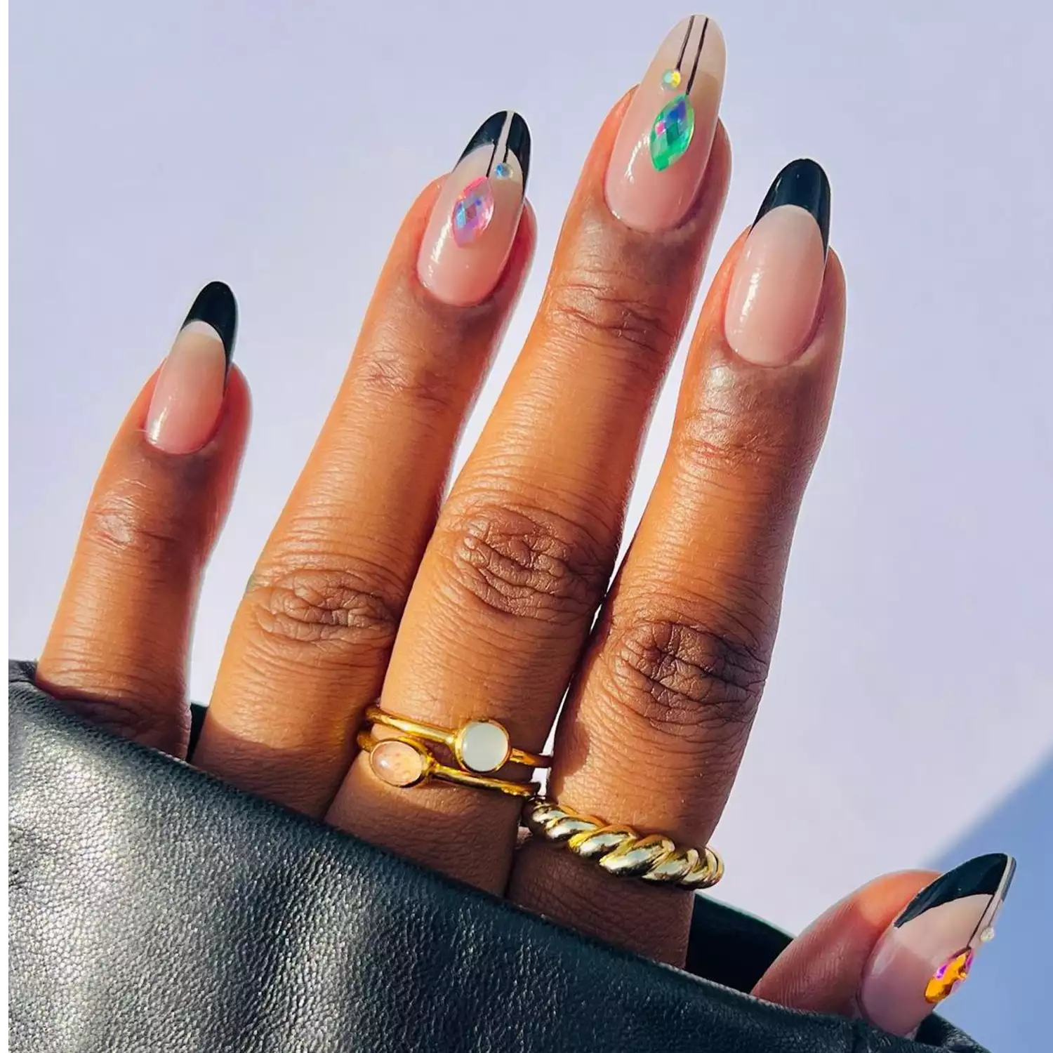 Manicure with black French tips, art deco lines, and colorful gemstones