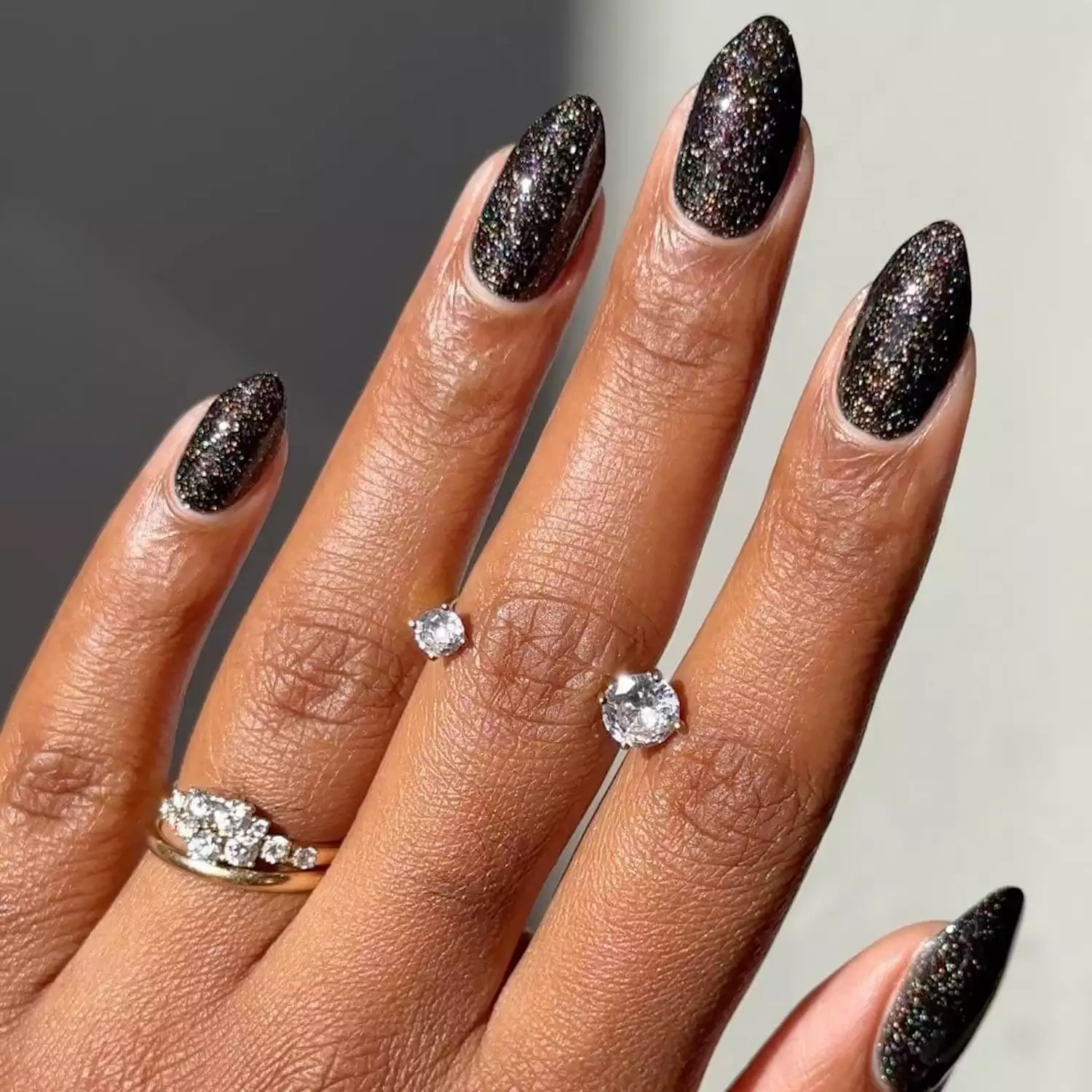 Black manicure with almond tips and gold glitter finish