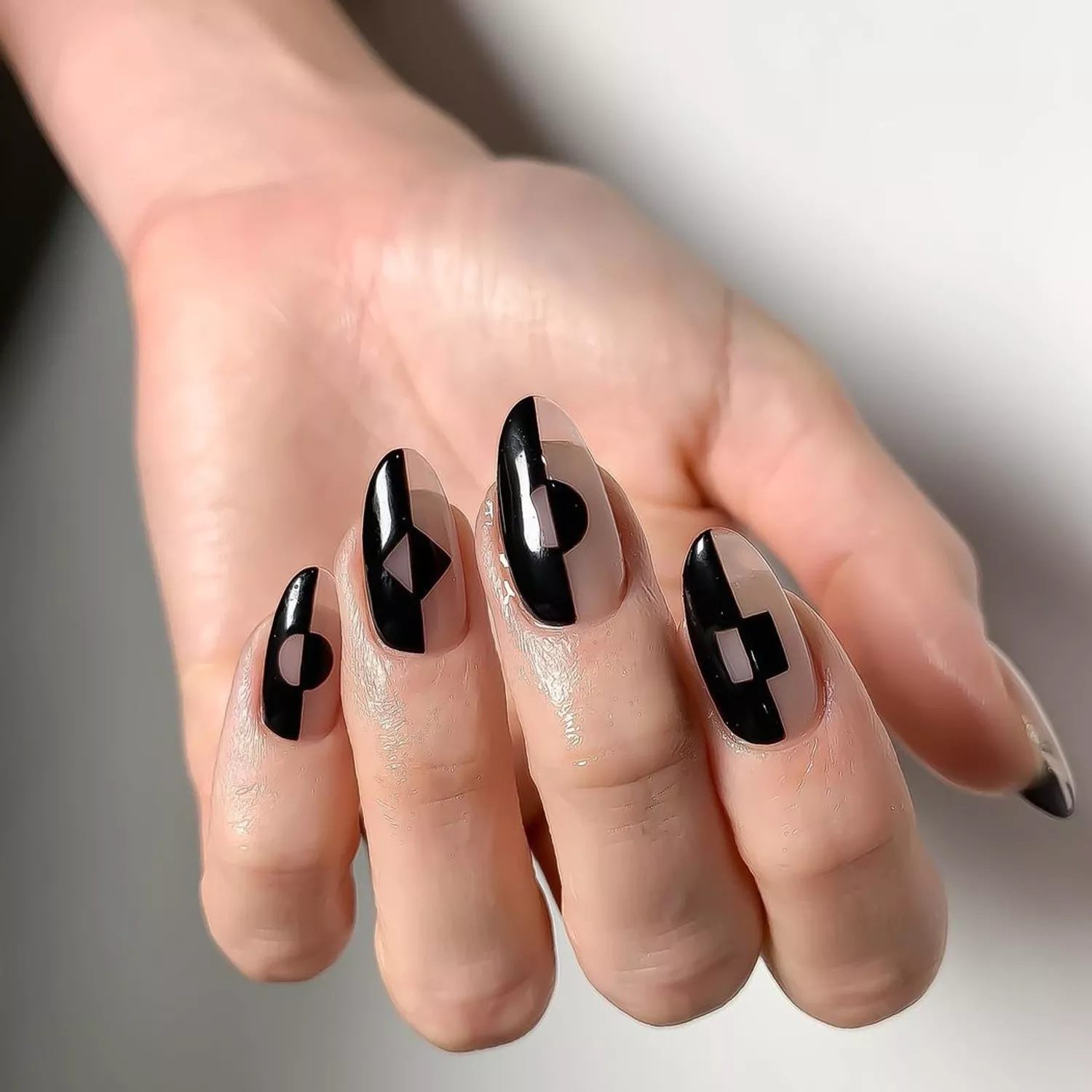 Manicure with half-black, half-sheer negative space design with graphic accents