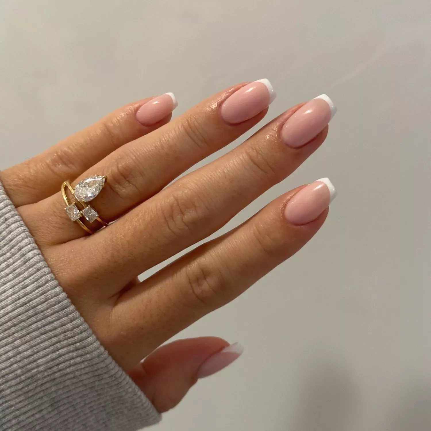 close up of nails with light pink base and thin white french tip