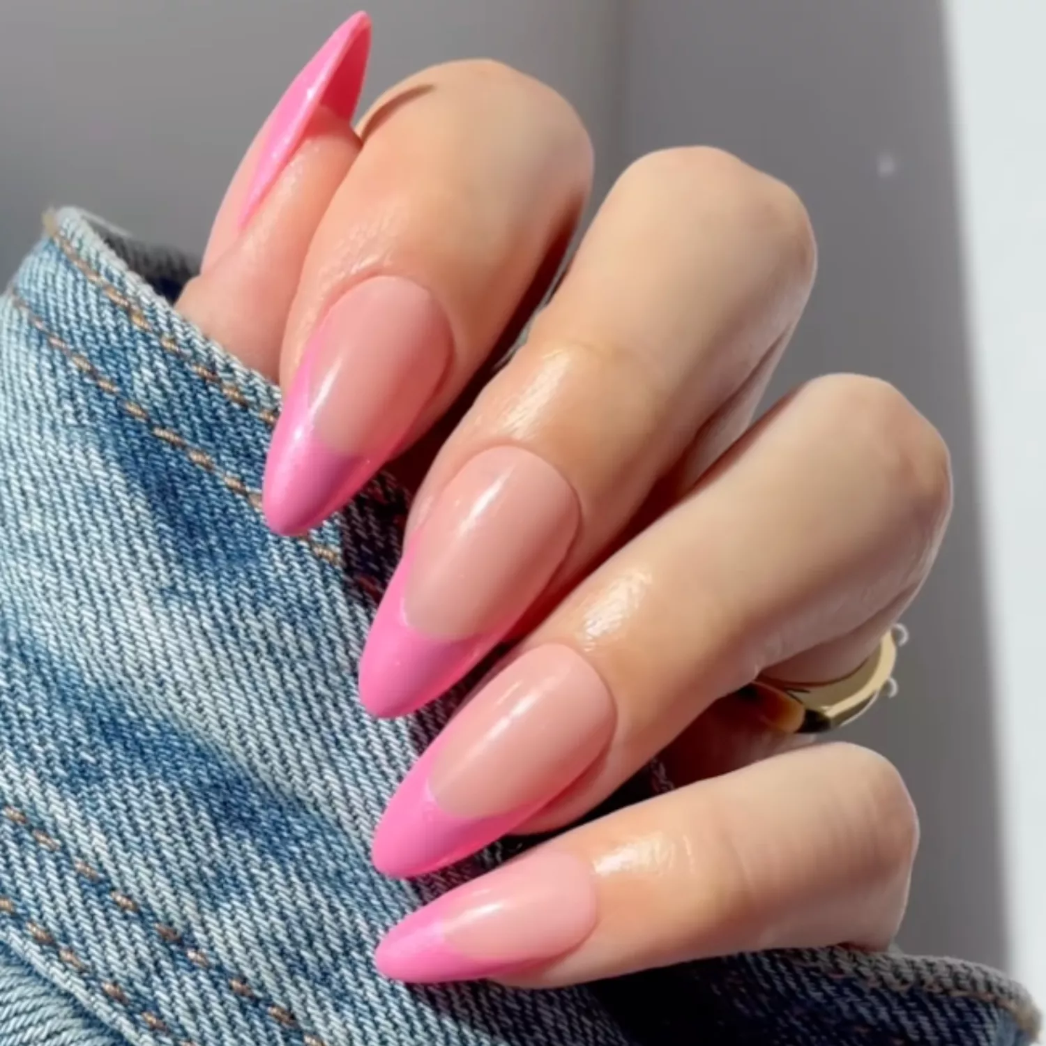 close up of nails with light nude base and pink french tip