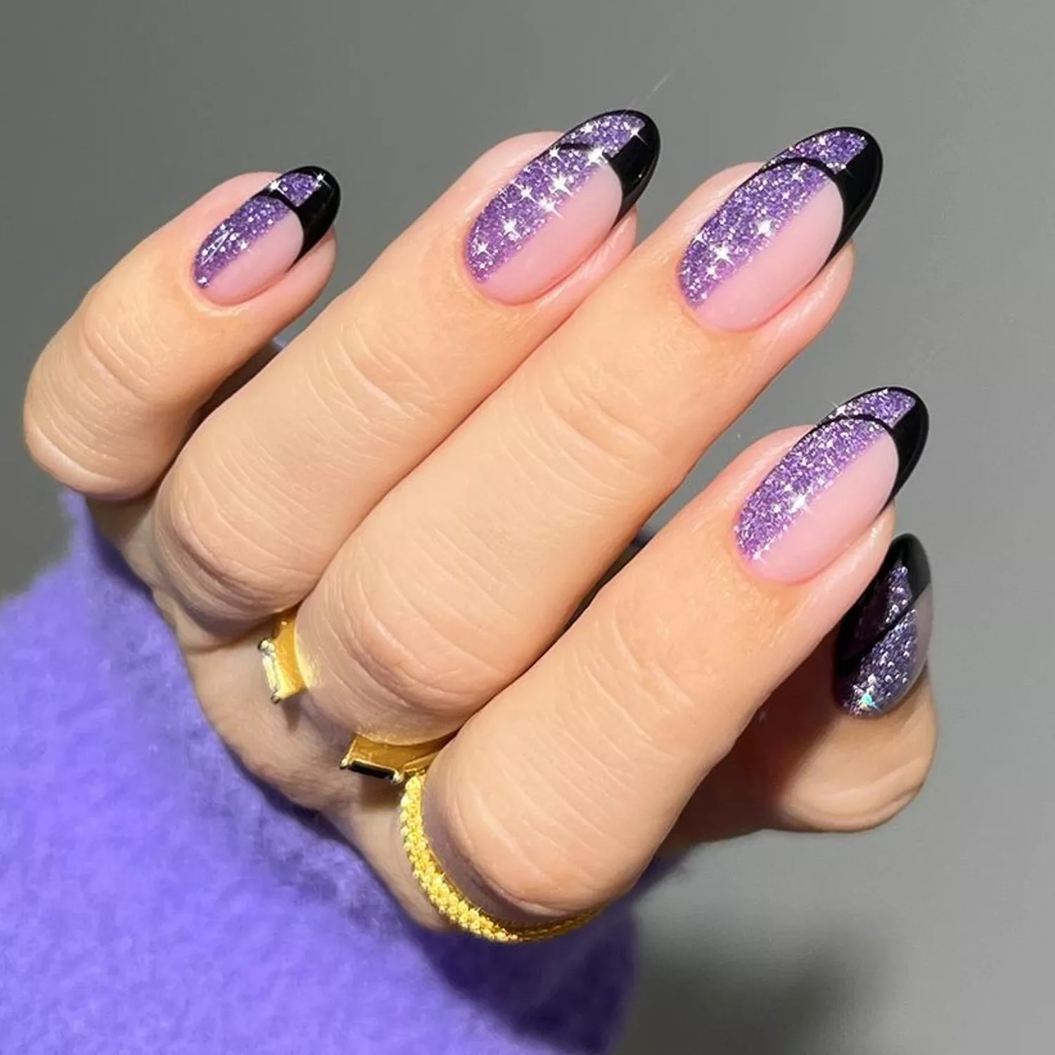 Close-up of manicure with half purple glitter polish and black art deco French tips