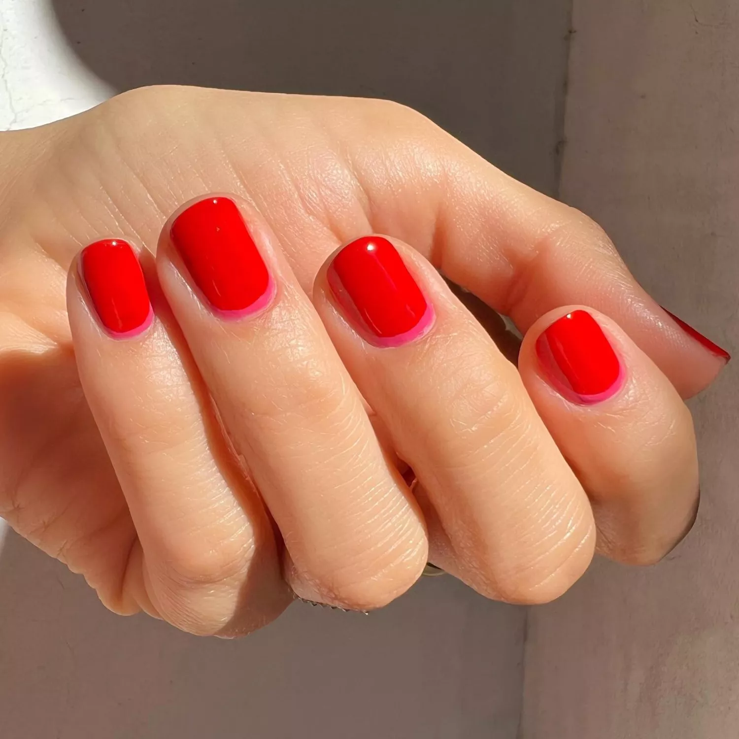 close up of nails with red polish and pink french along the cuticle bed