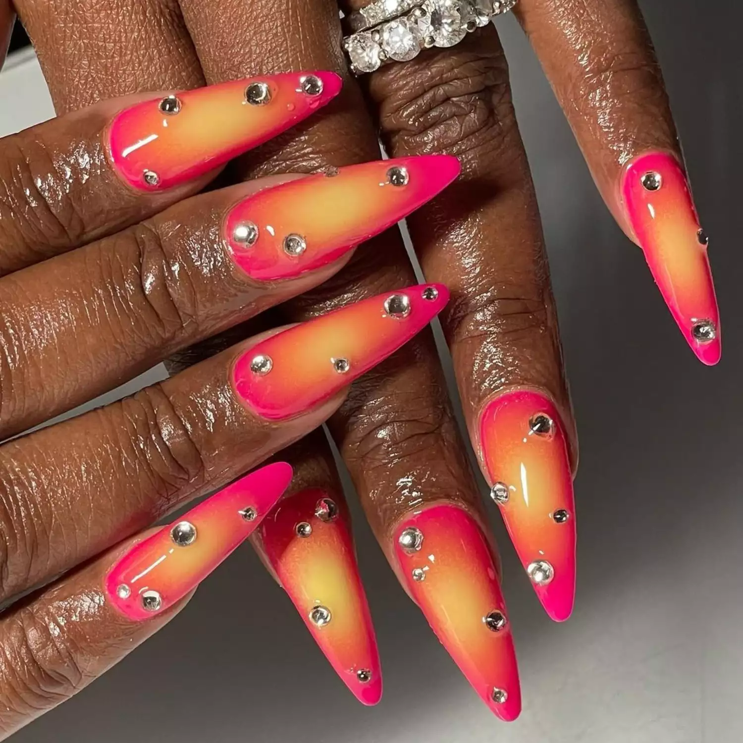 Neon pink and orange aura nails with rhinestones and diamond ring