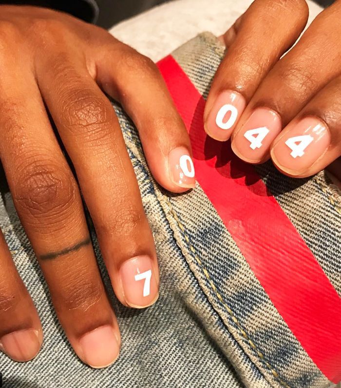 Two hands with number manicure against denim