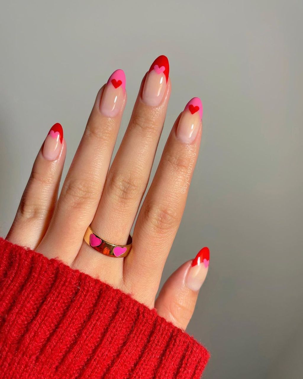 almond shaped cute Valentines Day nails with pink and red french tip designs and mini heart nail art