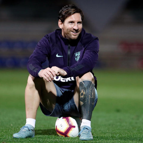 a man kneeling on the grass next to a football ball