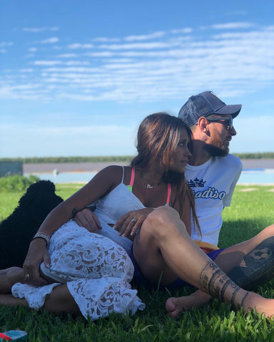 a man and woman sitting on grass by the water