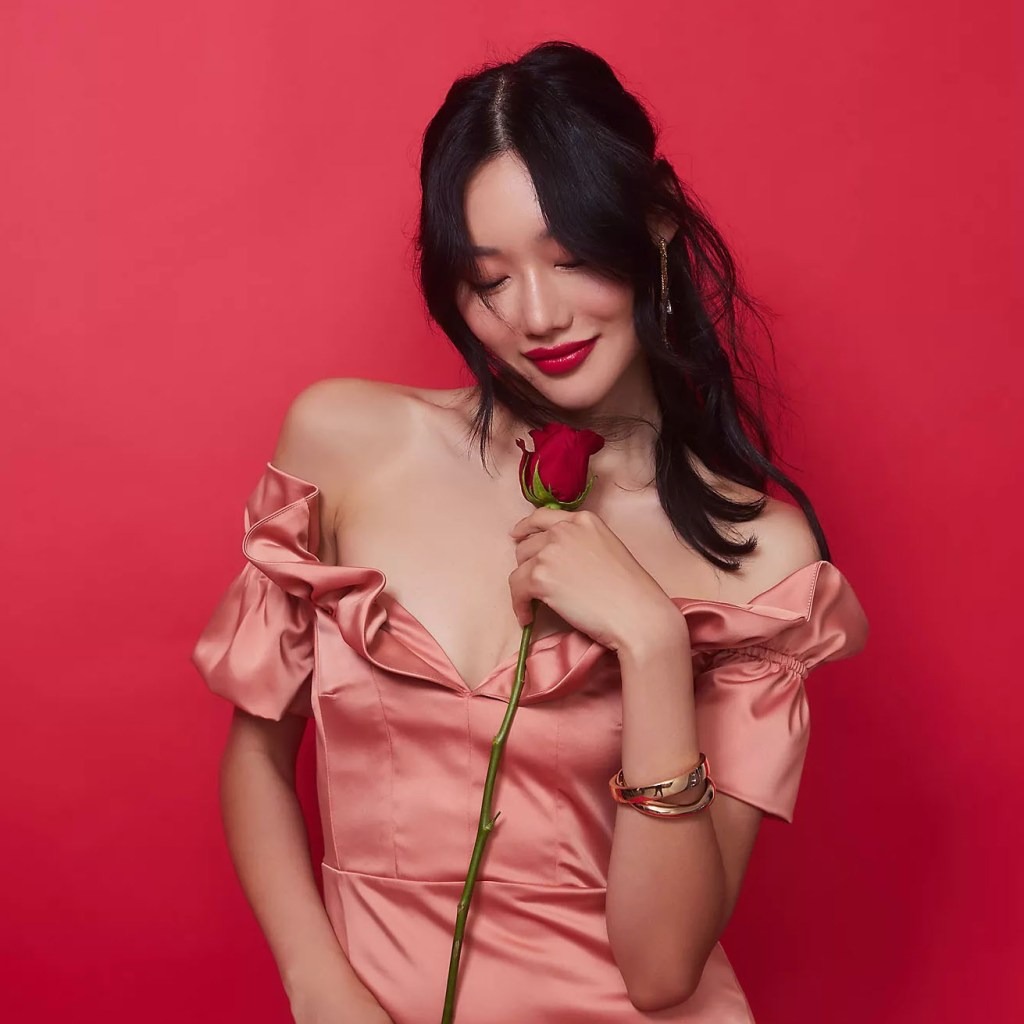 woman wearing a romantic ruffle off-the-shoulder midi dress and holding a rose