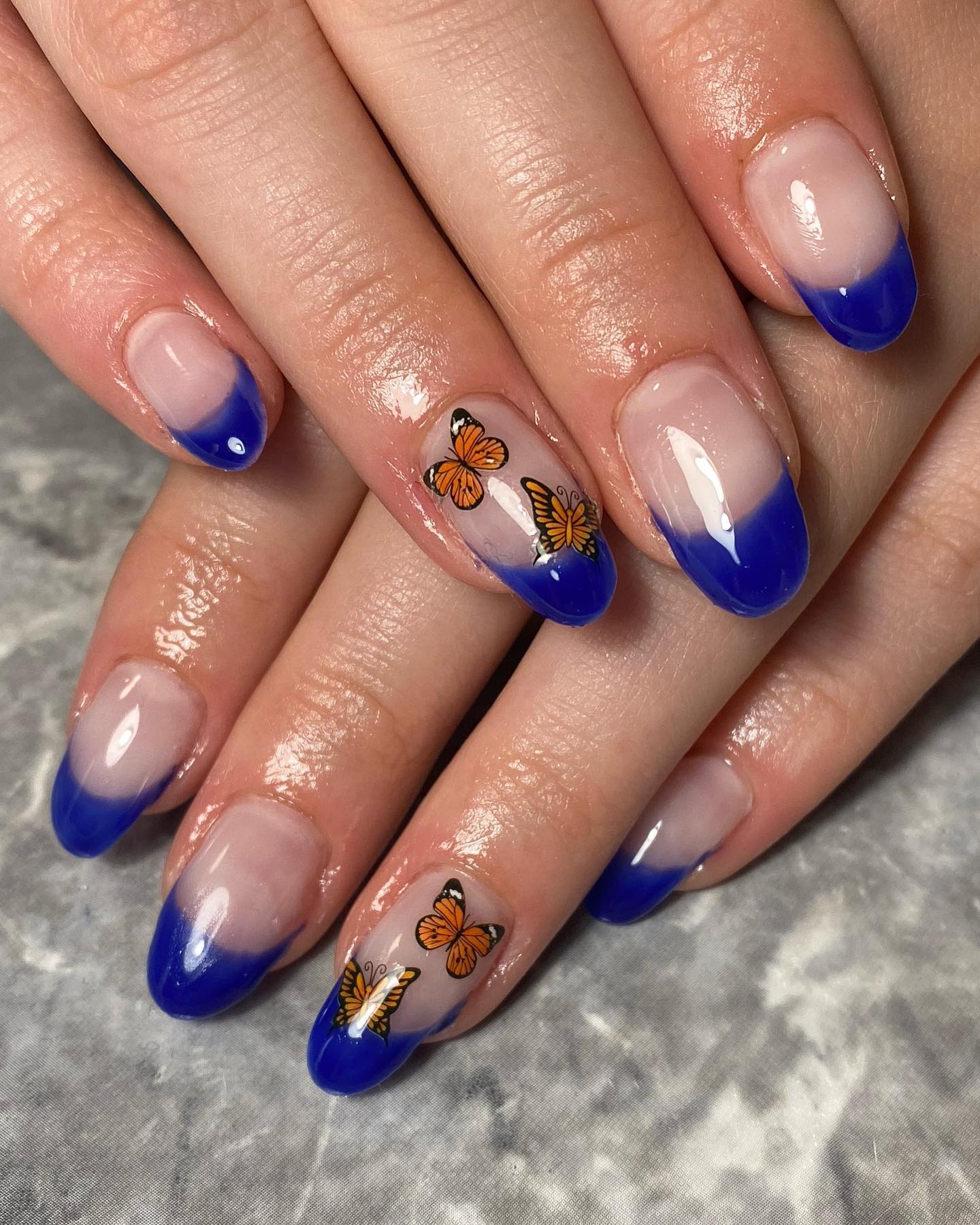 Neutral and white french manicure are classic but why not taking it to a new level? Use dark blue nail polish and some orange butterfly stickers.