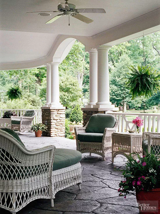 Front porch with potted plants, greenery, and wicker furniture