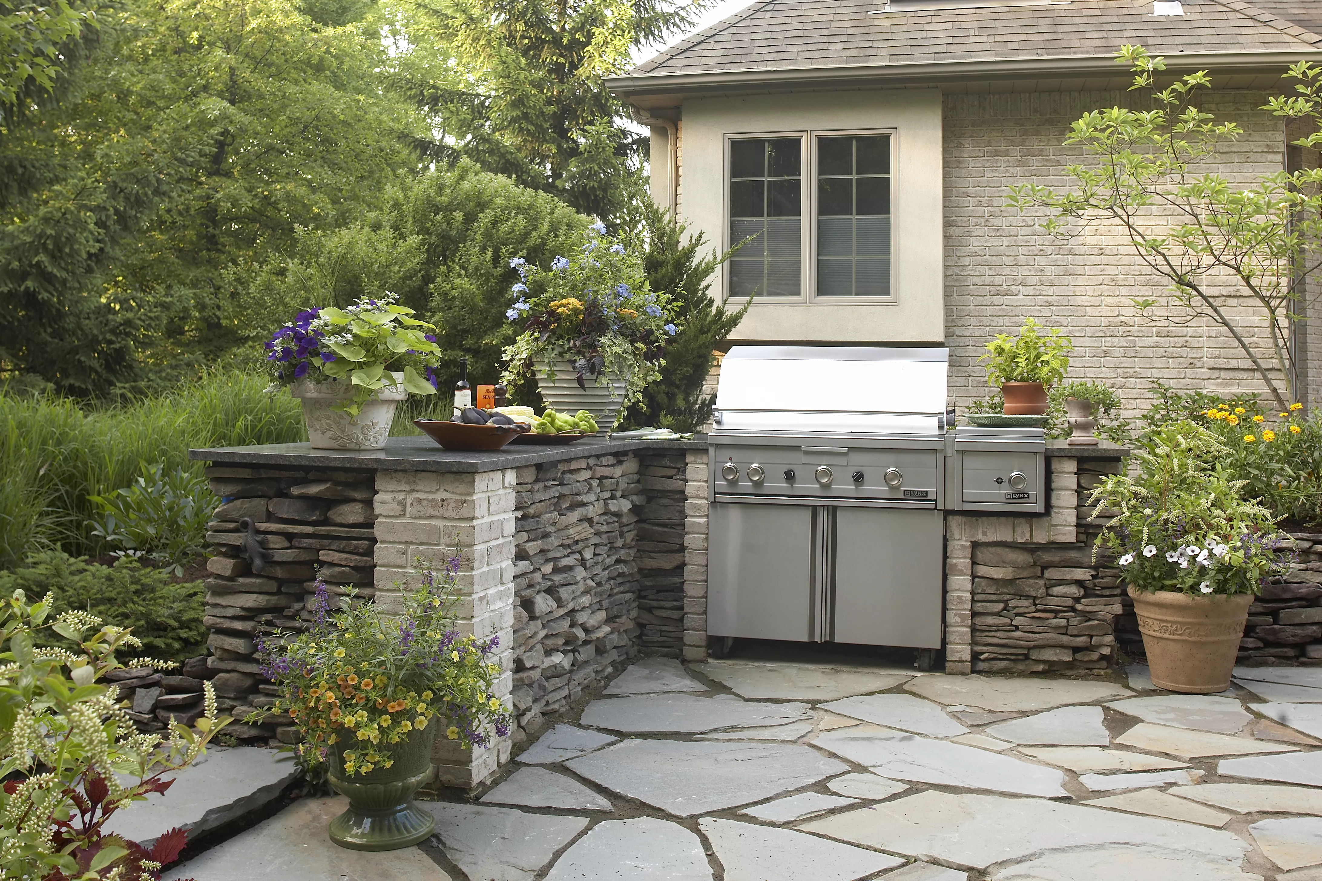 Patio with grill and stone built around it 