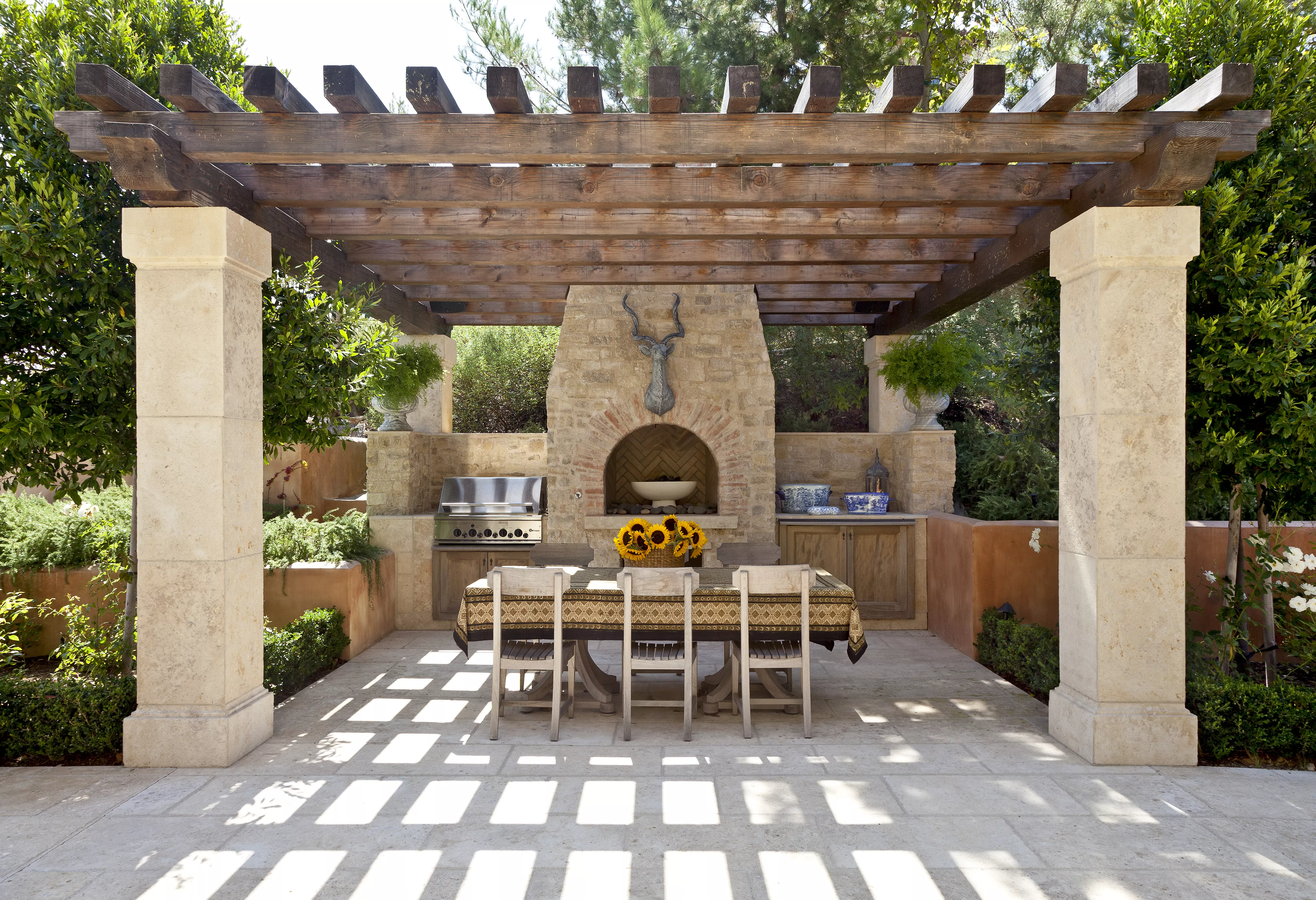 Outdoor kitchen with large wooden arbor.