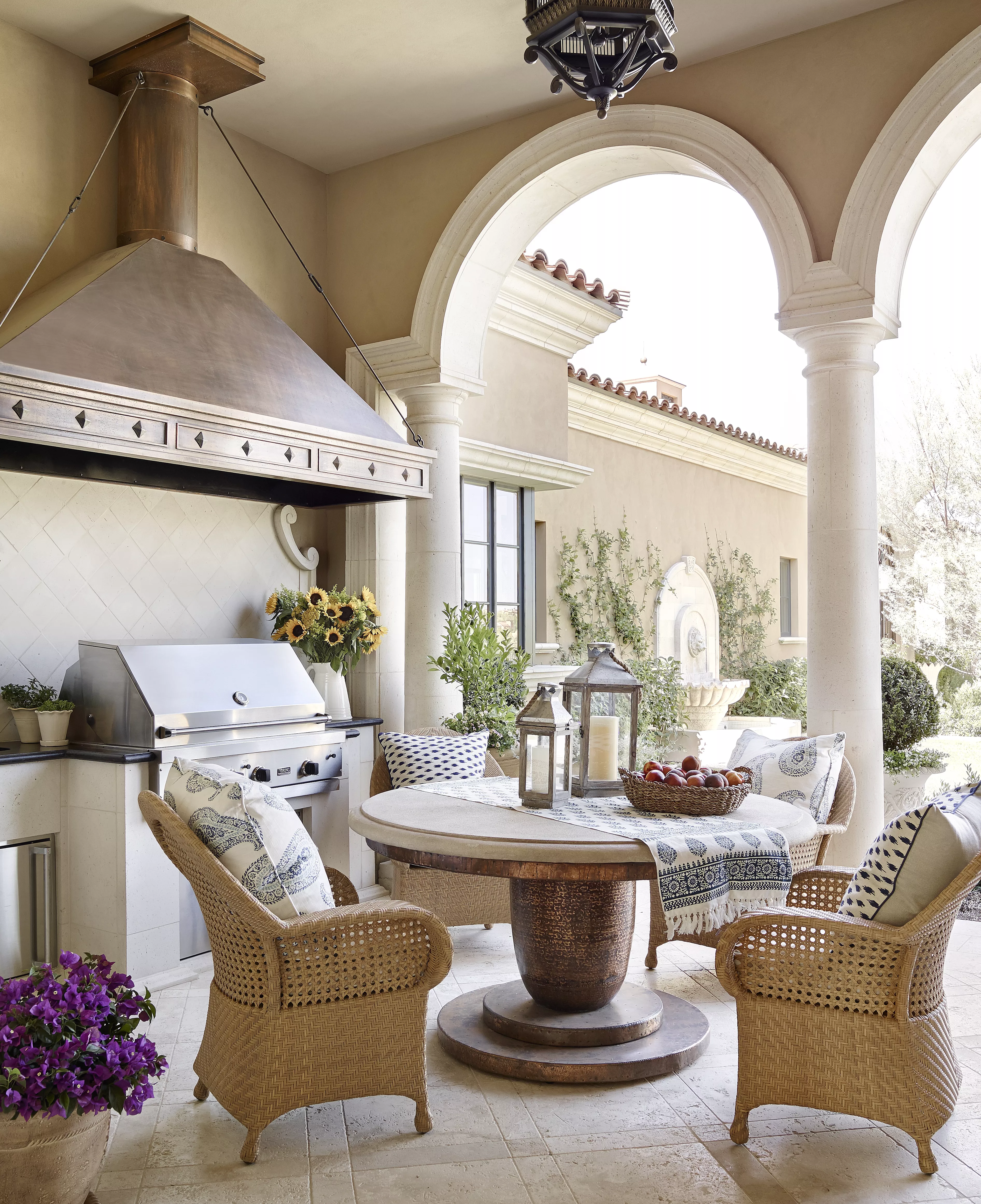 Covered patio with large stainless steel grill and dining table.