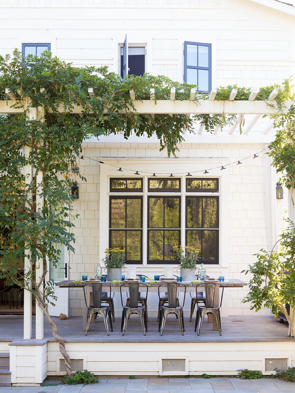 beige patio with rustic dinner table and modern black chairs