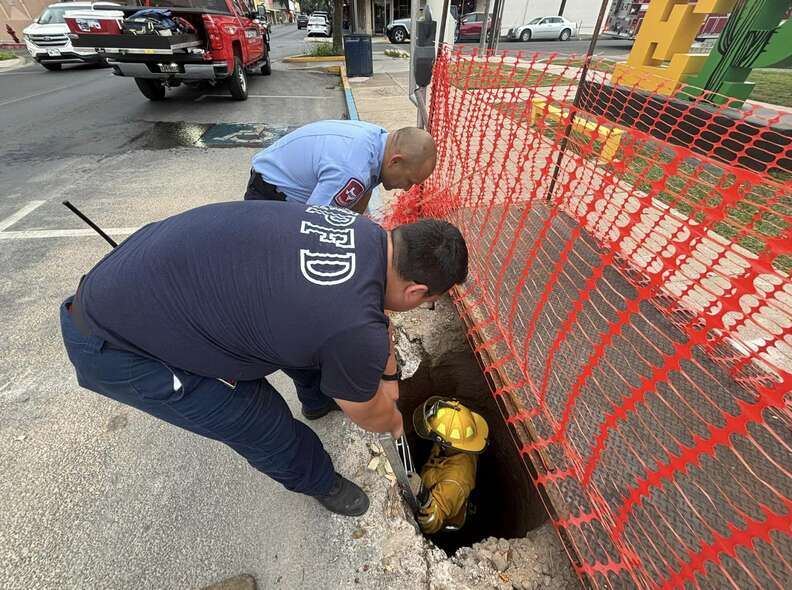 Firefighter in yellow helmet going down manhole