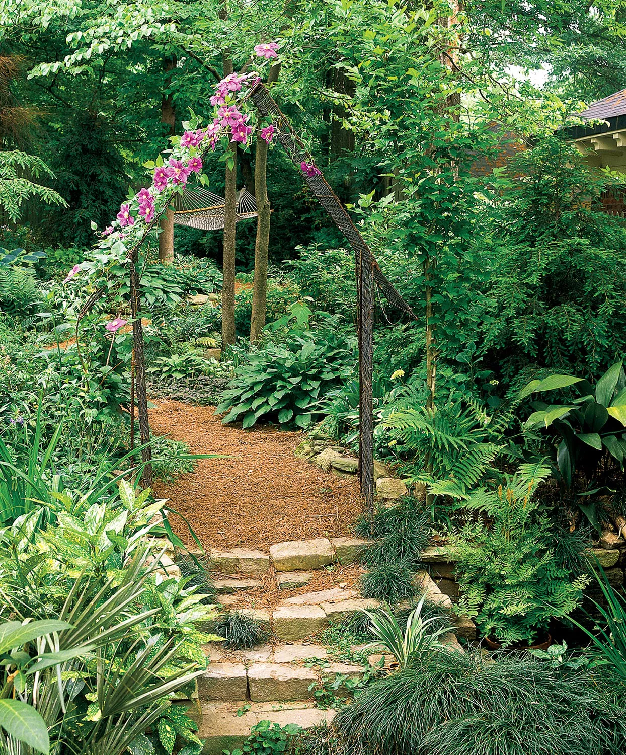 simple rustic arbor with purple climbing clematis and lush landscaping